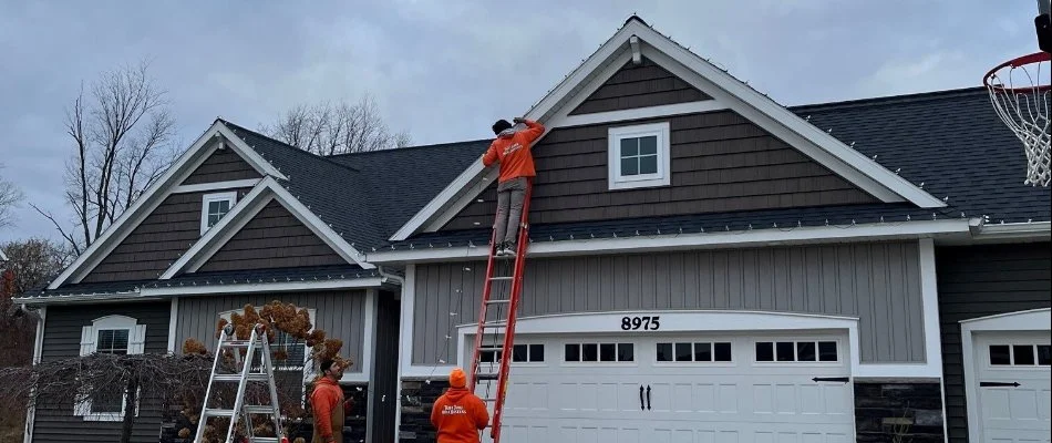 Professional holiday lighting installation crew on ladder